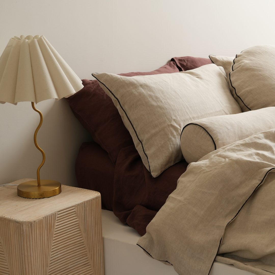 100% flax linen round piped feather filled cushion in natural oat/ black, close-up